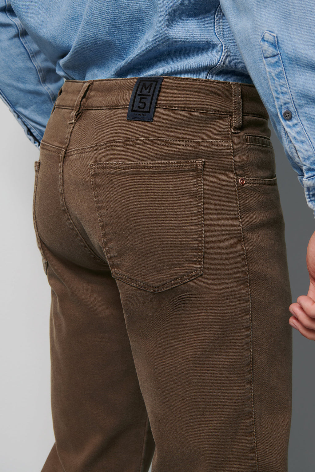 Brown pants with a visible brand label worn by a person in a blue shirt.
